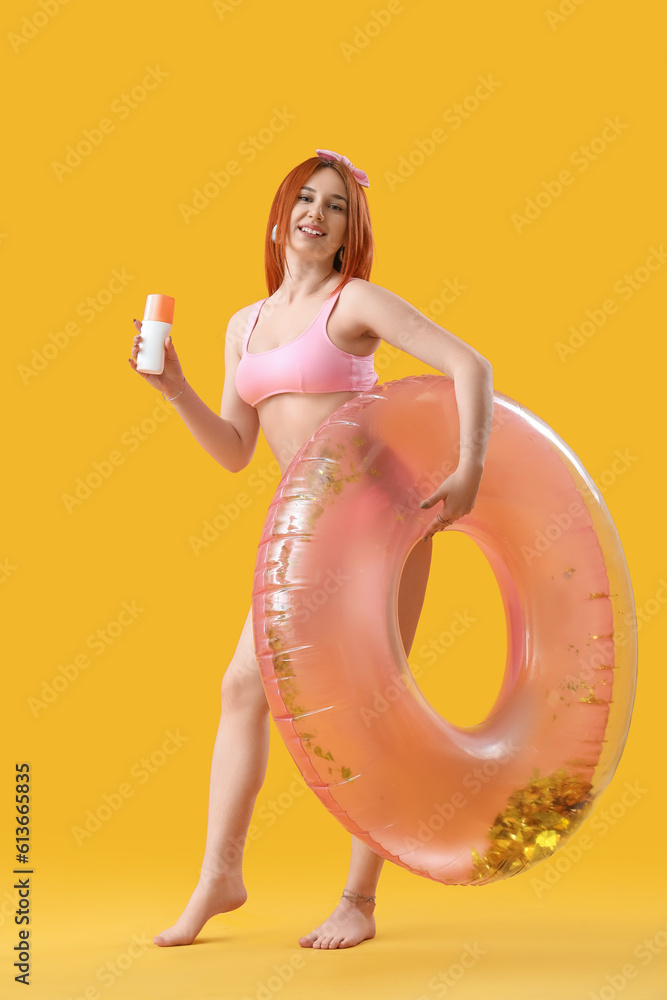 Young woman with sunscreen cream and inflatable ring on yellow background