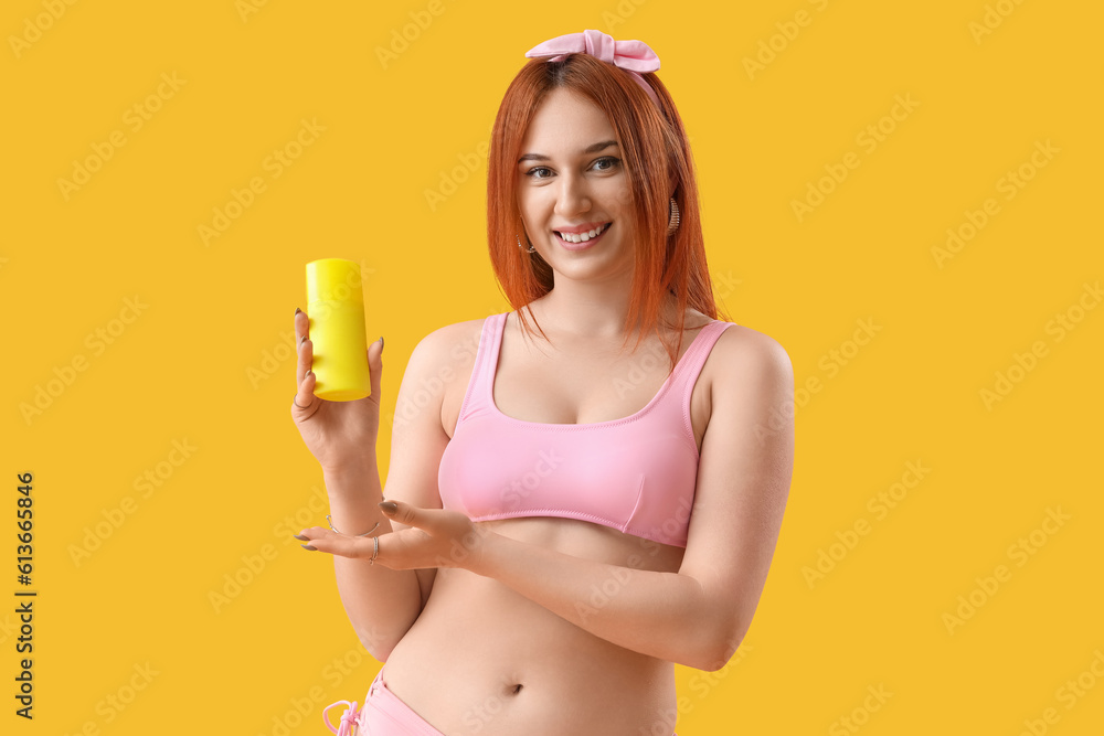 Young woman with sunscreen cream on yellow background