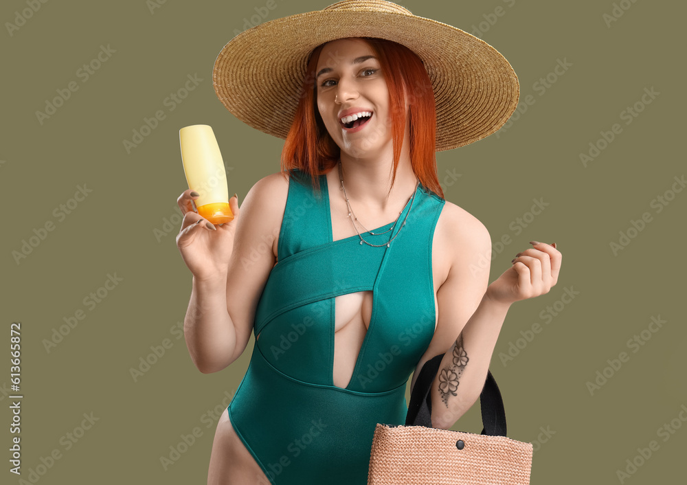 Young woman with sunscreen cream and beach bag on green background