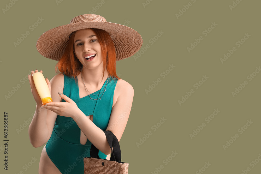 Young woman with sunscreen cream and beach bag on green background