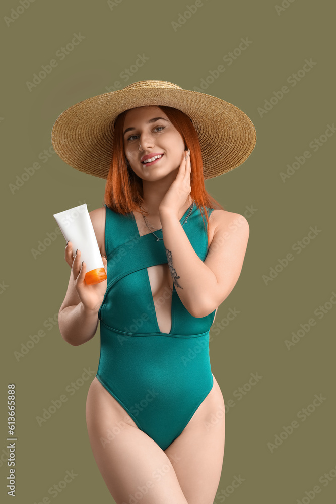 Young woman with sunscreen cream on green background