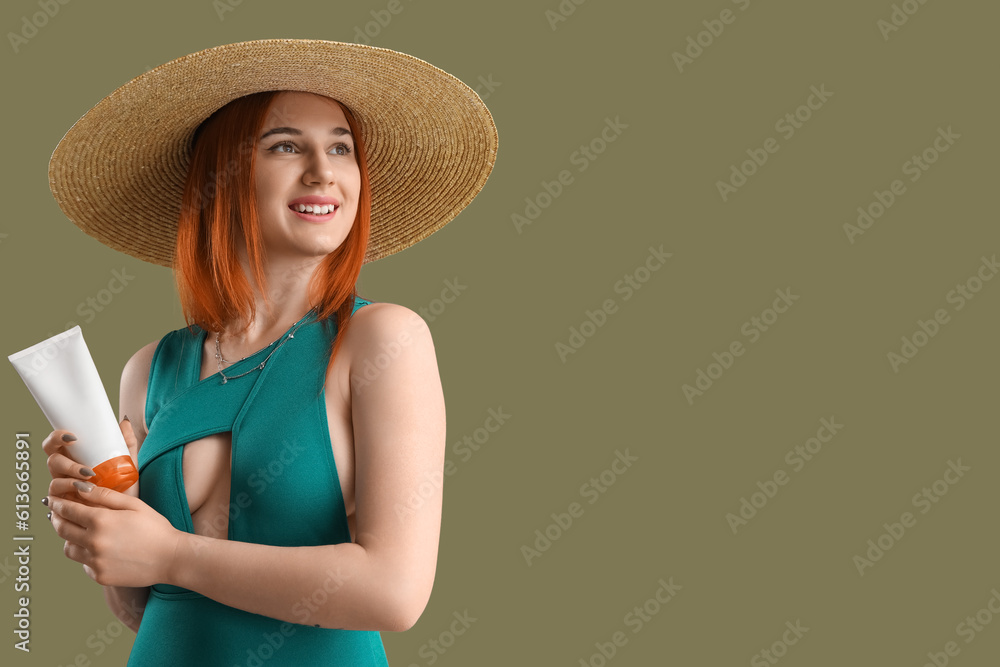 Young woman with sunscreen cream on green background