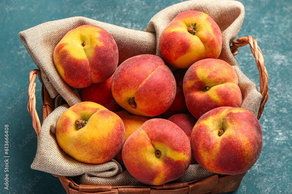 Wicker basket with sweet peaches on blue table