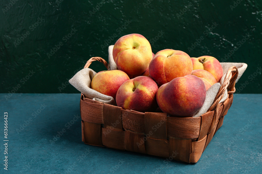 Wicker basket with sweet peaches on blue table