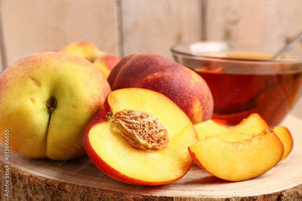 Board with sweet peaches on beige wooden background