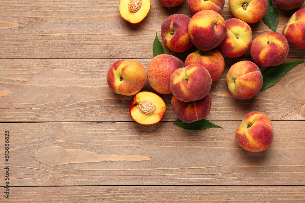 Many sweet peaches and leaves on wooden background