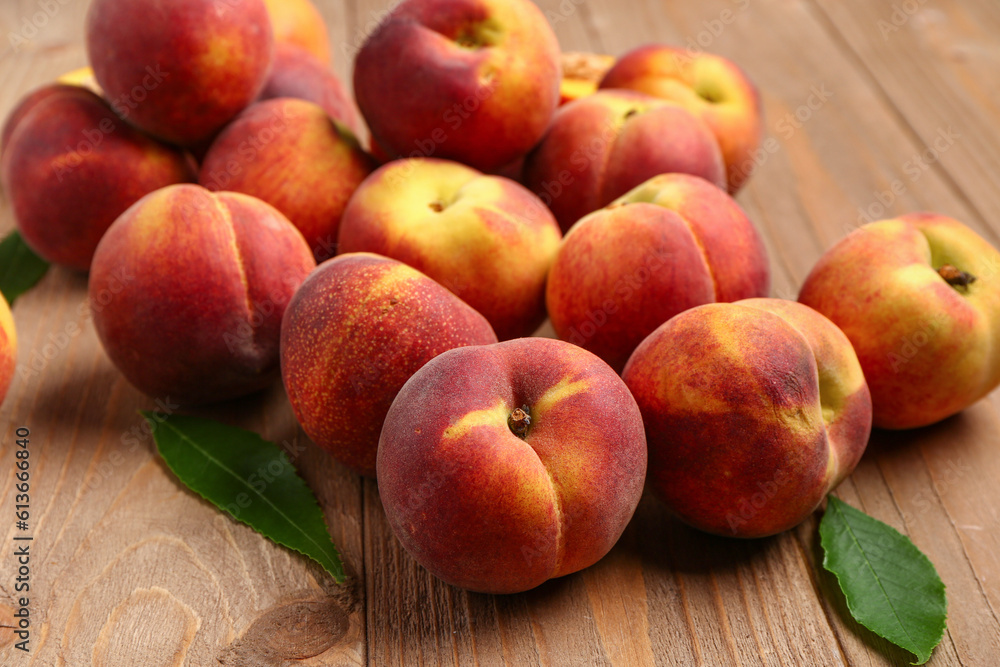 Many sweet peaches and leaves on wooden background