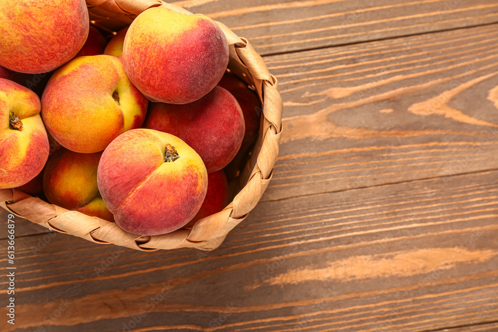 Wicker bowl with sweet peaches on wooden background