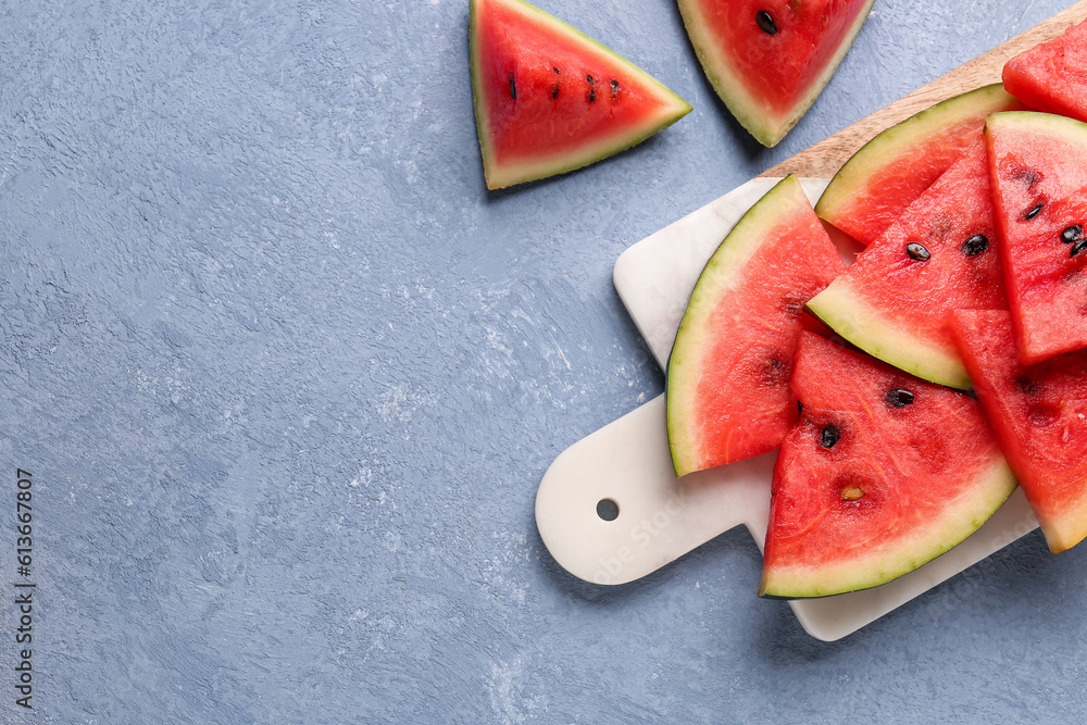 Board with pieces of fresh watermelon on blue background