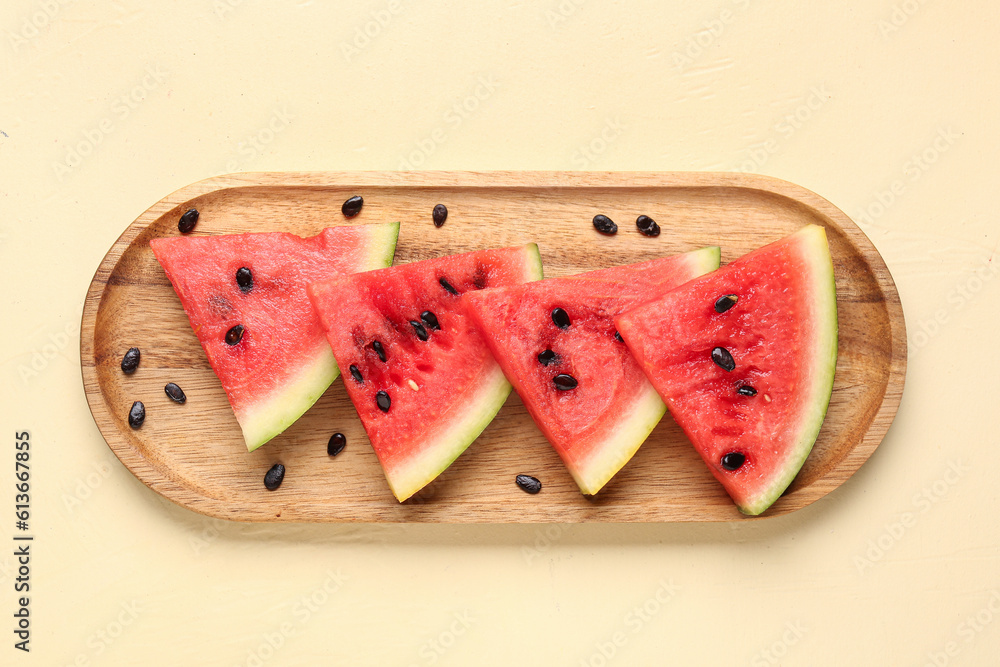 Board with pieces of fresh watermelon and seeds on beige background