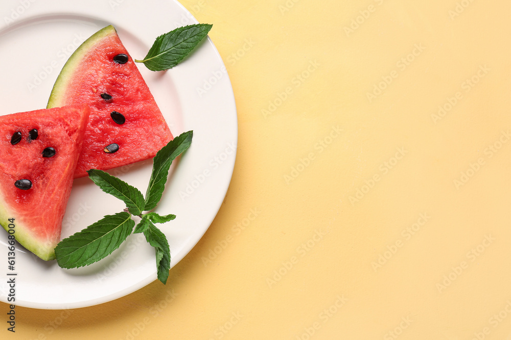 Plate with pieces of fresh watermelon and mint on yellow background