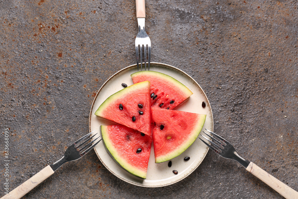 Plate with pieces of fresh watermelon and seeds on dark background