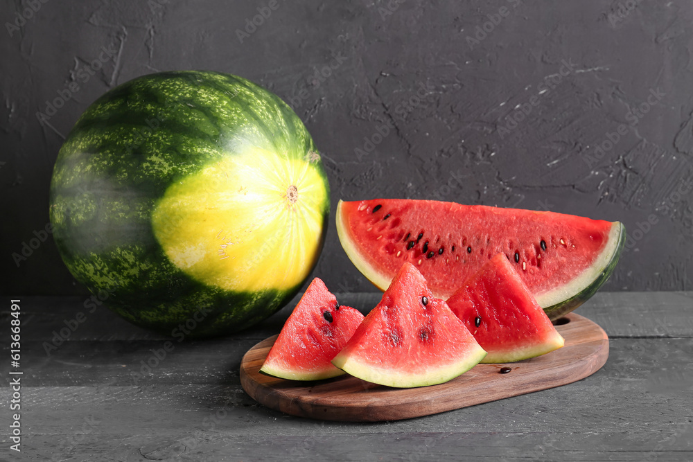 Board with pieces of fresh watermelon on black wooden table