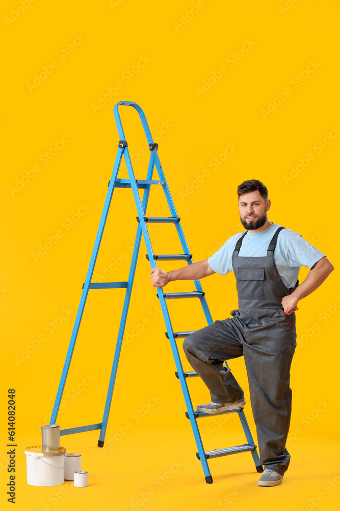 Male worker with ladder and cans of paint on yellow background