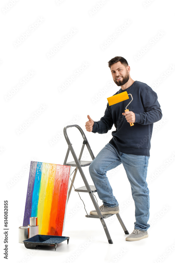 Young man with paint roller and ladder on white background