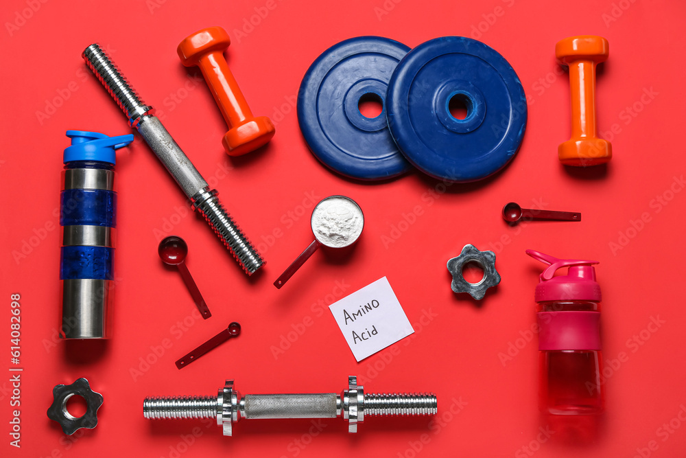 Composition with sports equipment, bottle of water and amino acid supplement on red background