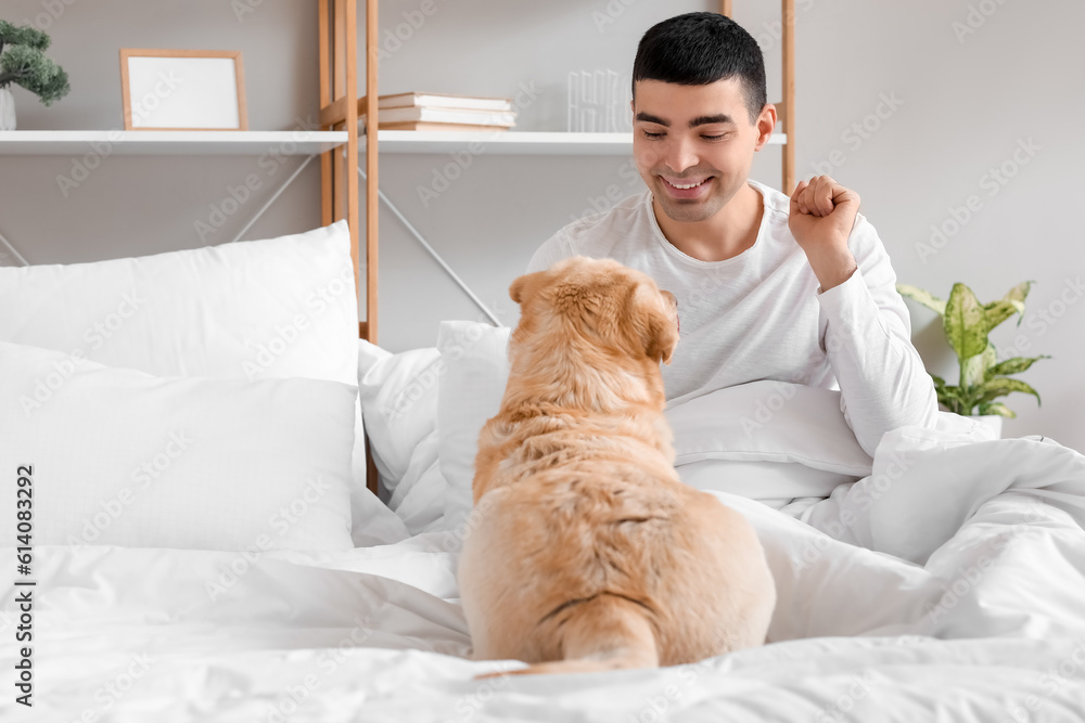 Young man with cute Labrador dog sitting in bedroom