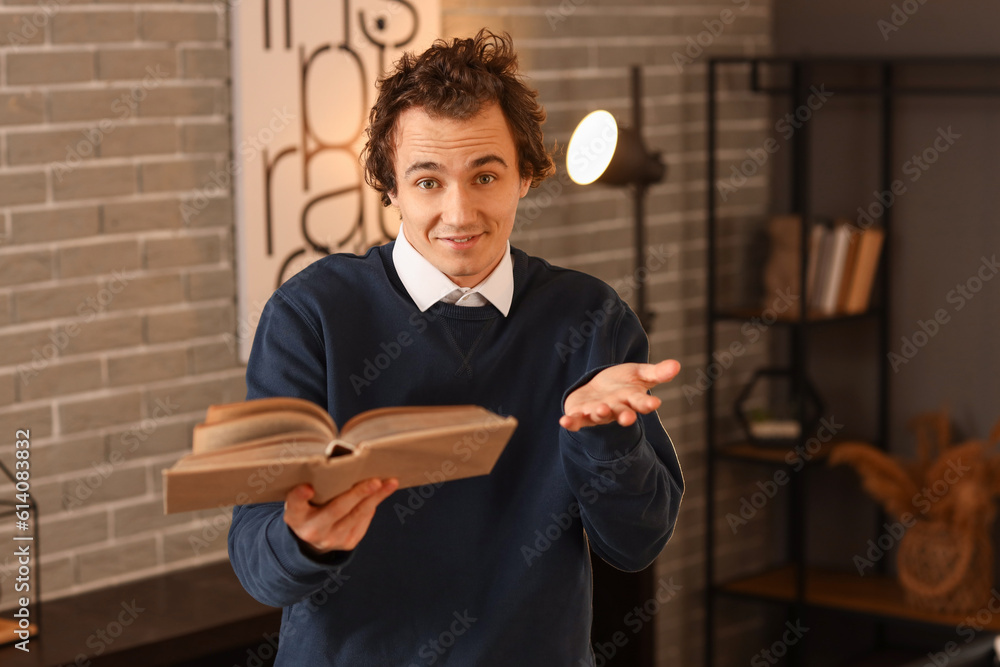 Young man reading book at home late in evening