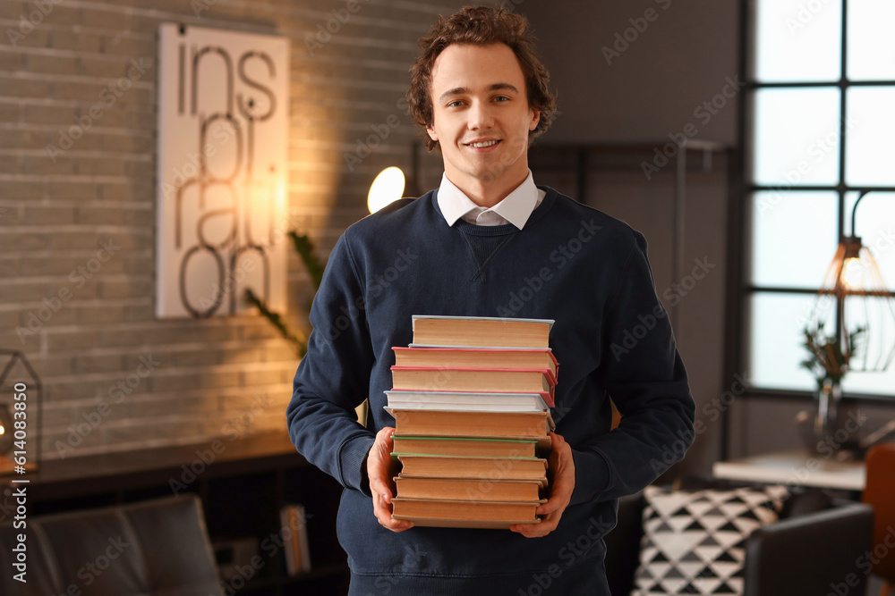 Young man with stack of books at home late in evening