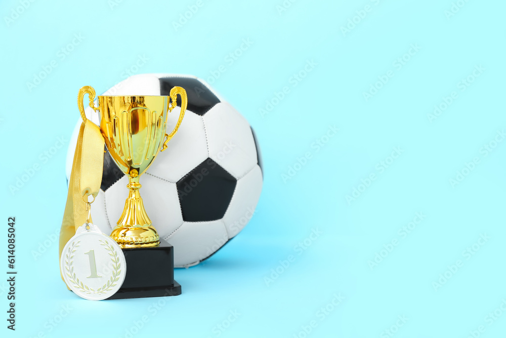 Gold cup with first place medal and soccer ball on blue background