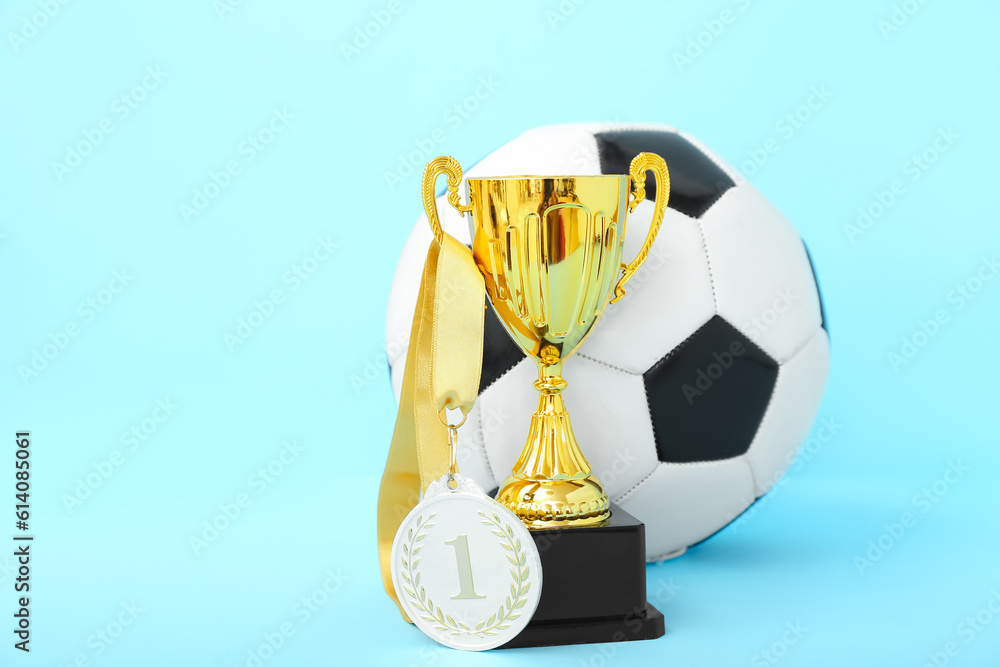 Gold cup with first place medal and soccer ball on blue background