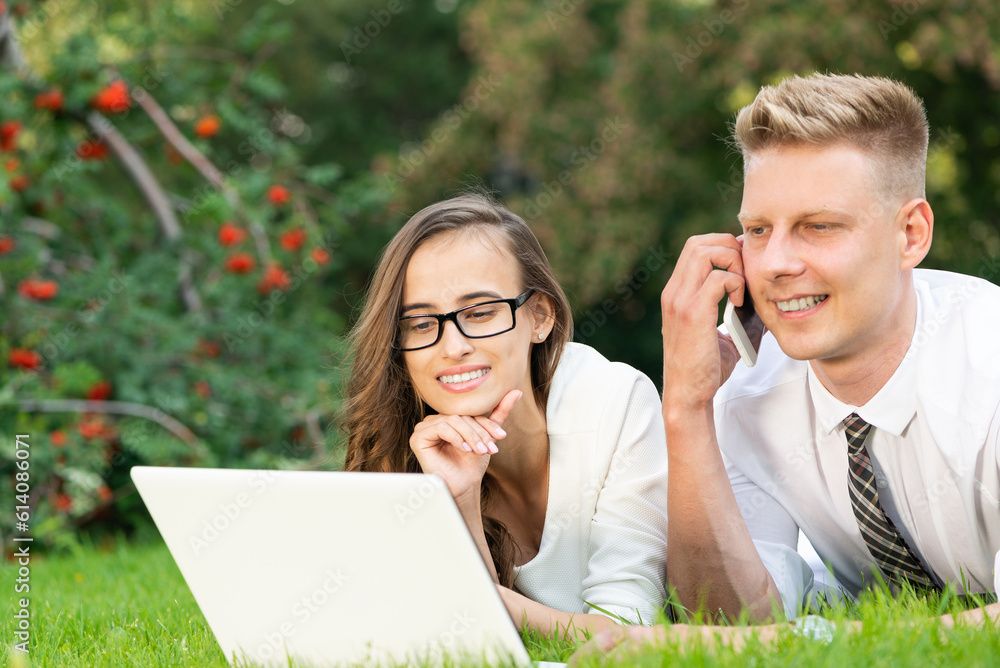 businessman and businesswoman with a laptop in a city park