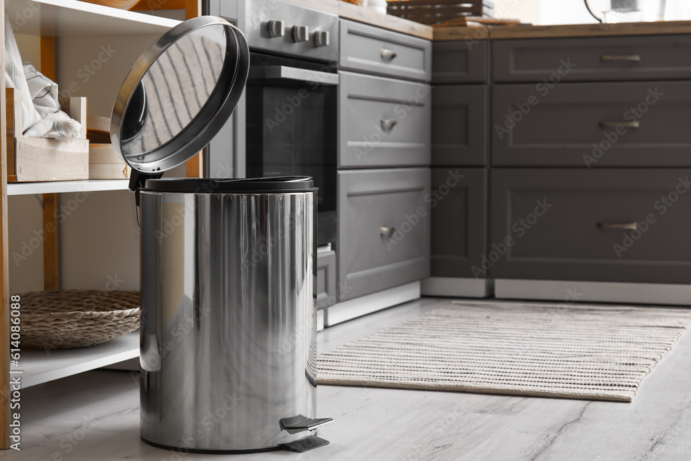 Opened metallic trash bin on floor in modern kitchen