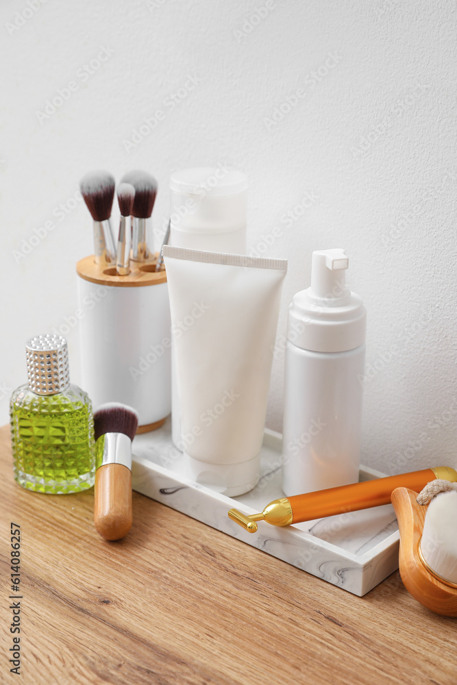 Bath accessories with brushes on table near light wall