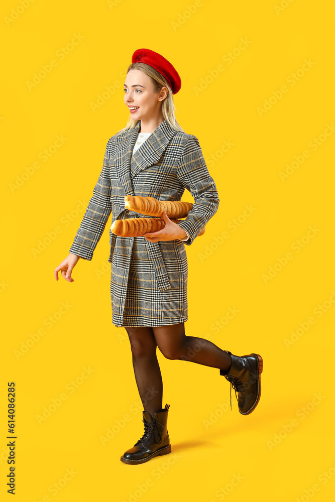 Stylish young woman with baguettes on yellow background