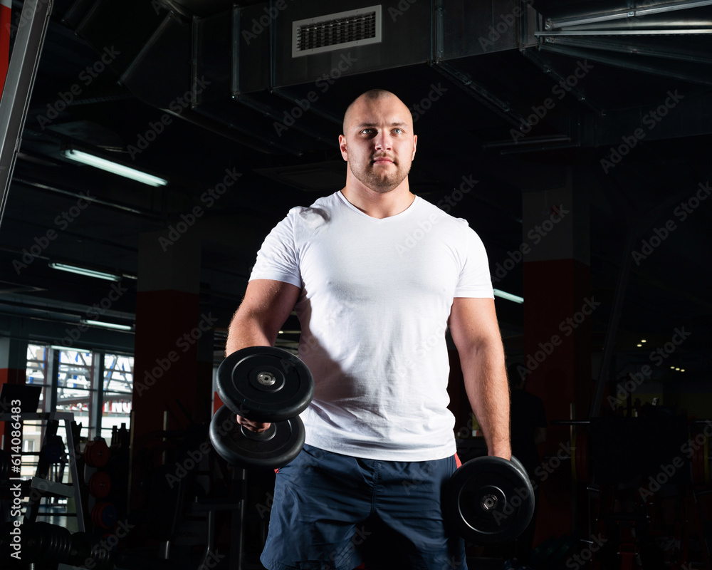 Male bodybuilder engaged with dumbbells in the gym