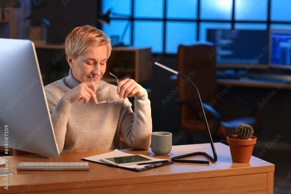 Mature female programmer working in office at night