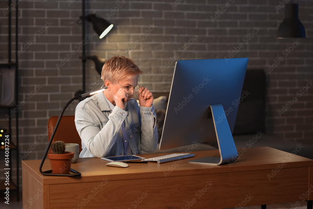 Mature female programmer working with computer in office at night