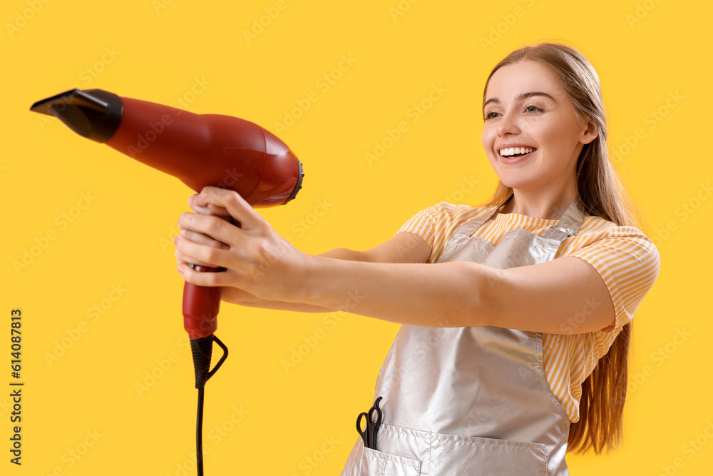 Female hairdresser with dryer on yellow background