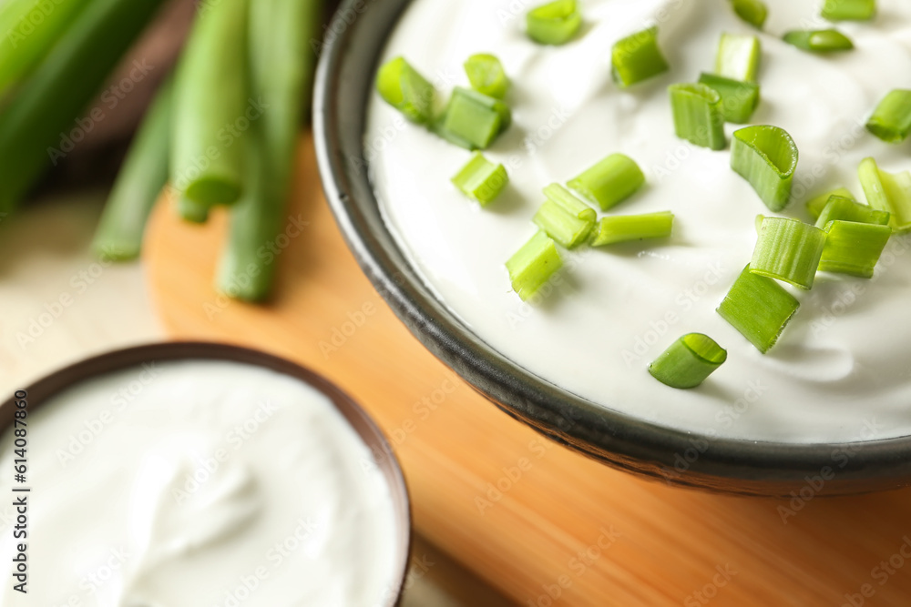 Composition with sour cream and sliced green onion on wooden table