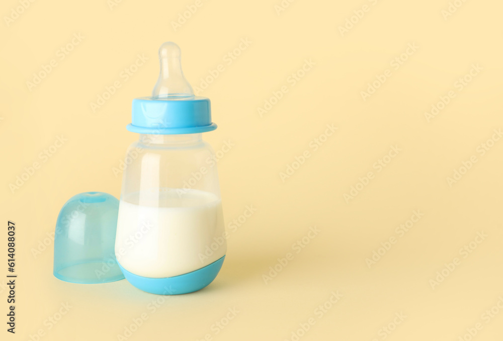 Bottle with milk for baby on pale yellow background