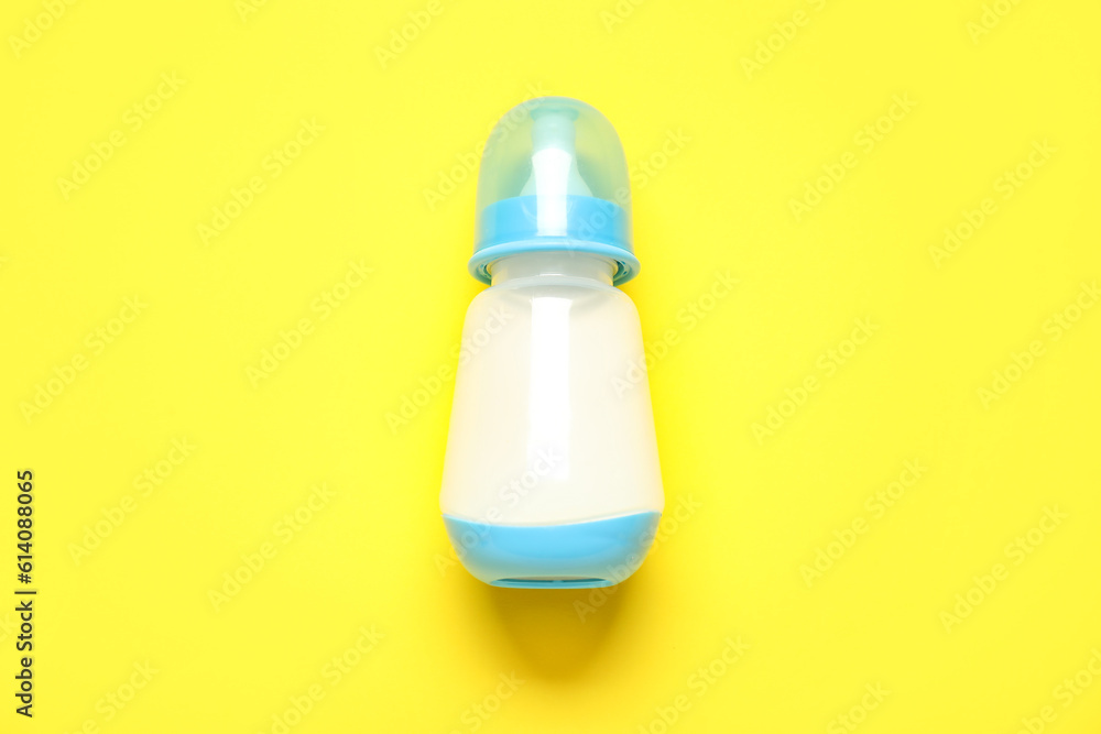 Bottle with milk for baby on yellow background