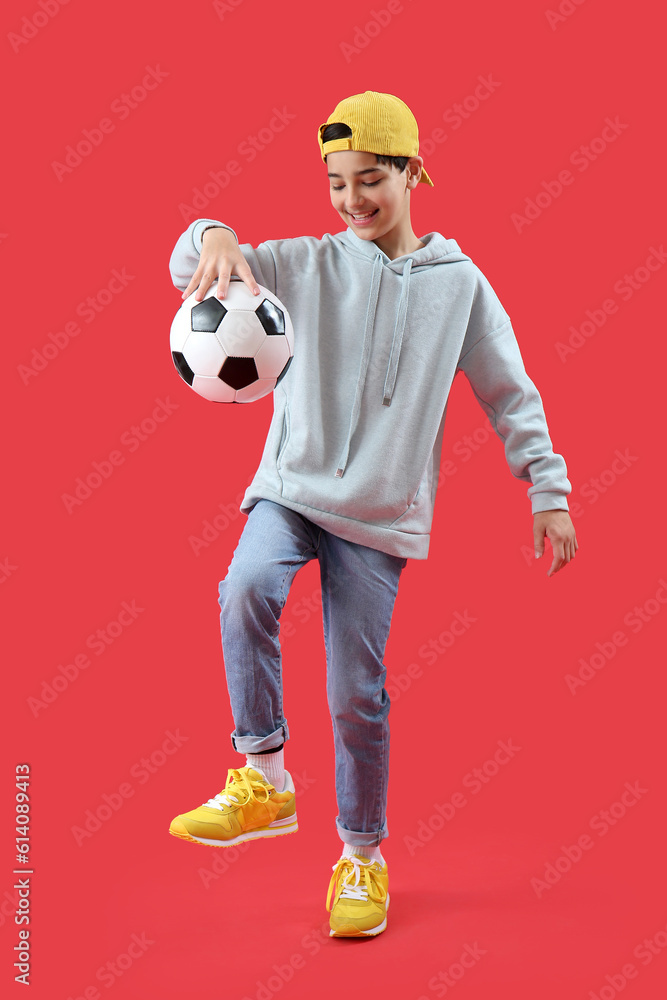 Little boy playing with soccer ball on red background