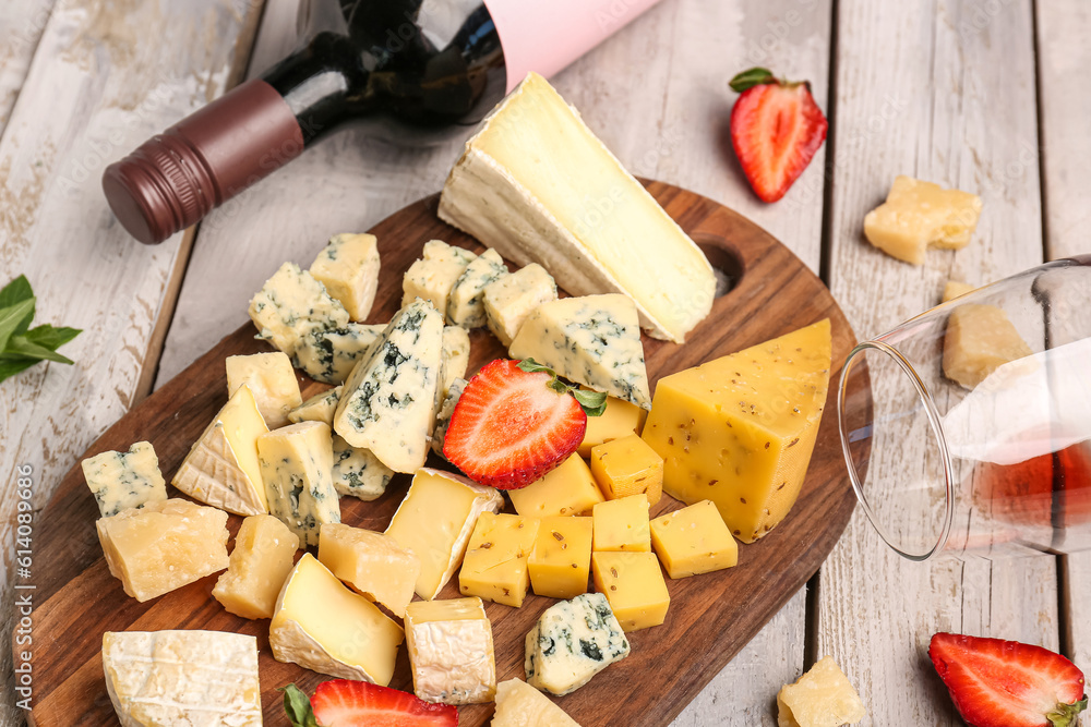 Board with pieces of tasty cheese on light wooden background