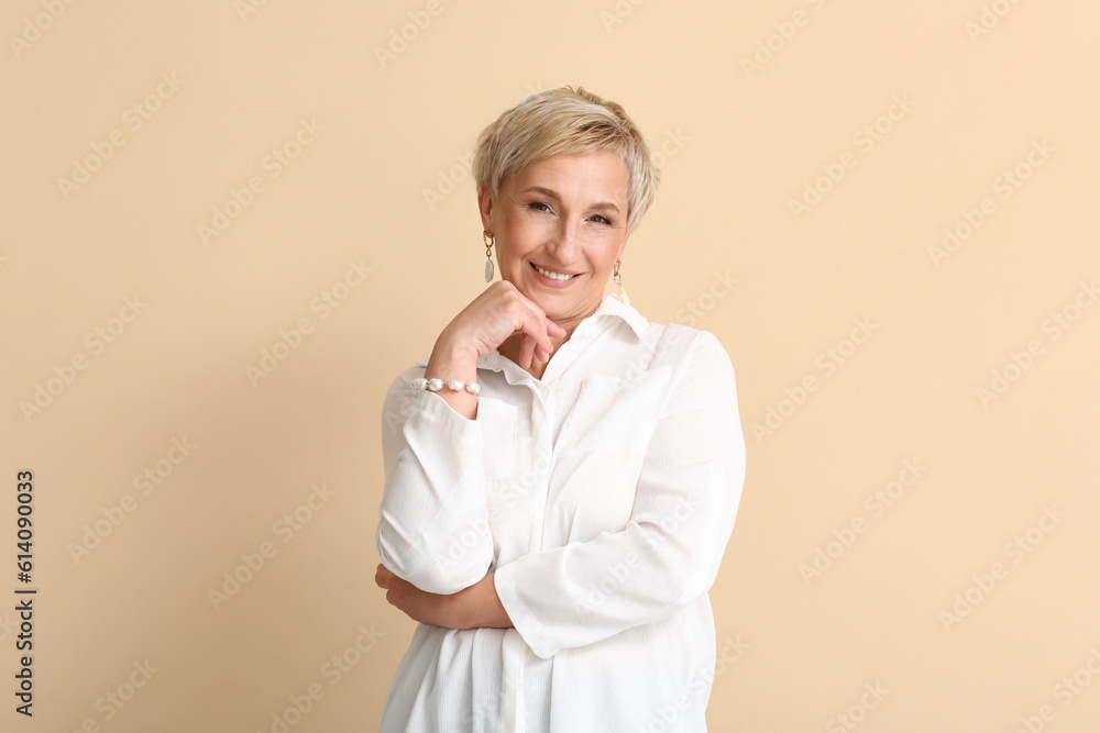 Mature blonde woman in white shirt on beige background