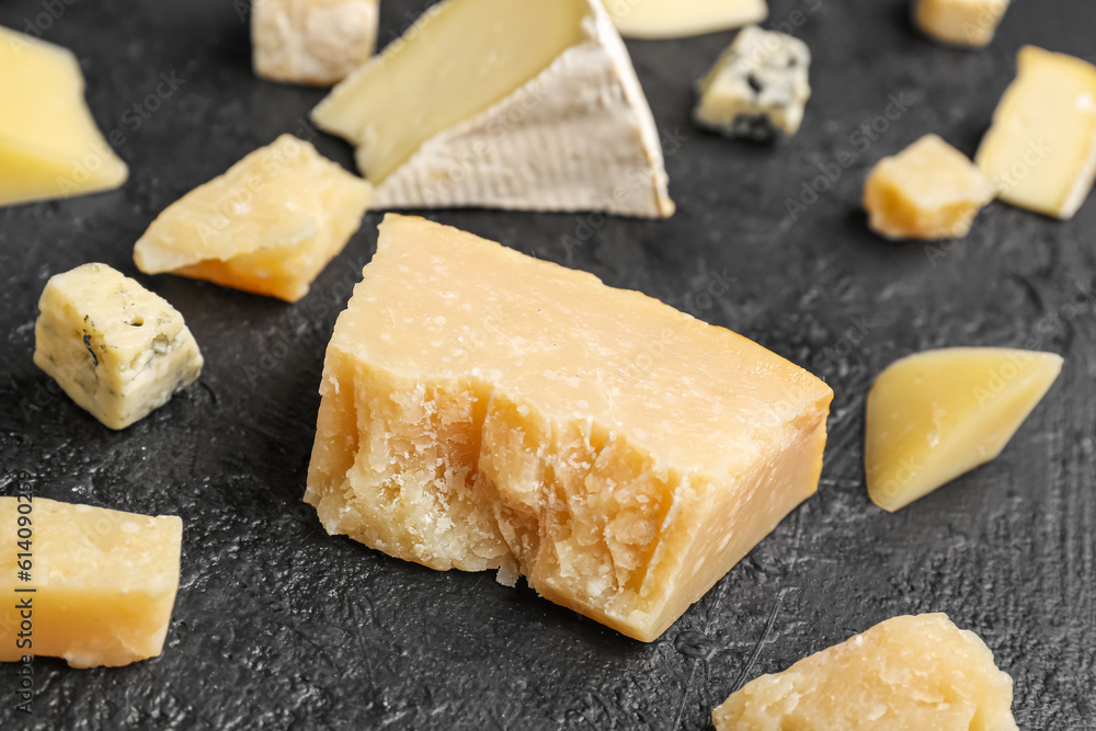 Pieces of tasty cheese on dark background