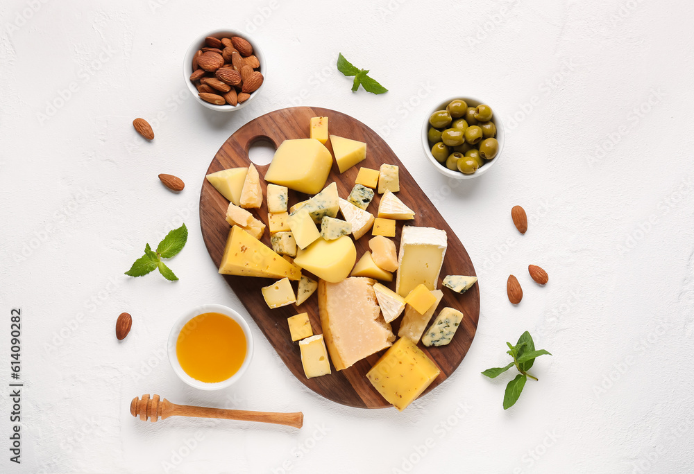 Wooden board with pieces of tasty cheese, nuts and honey on light background