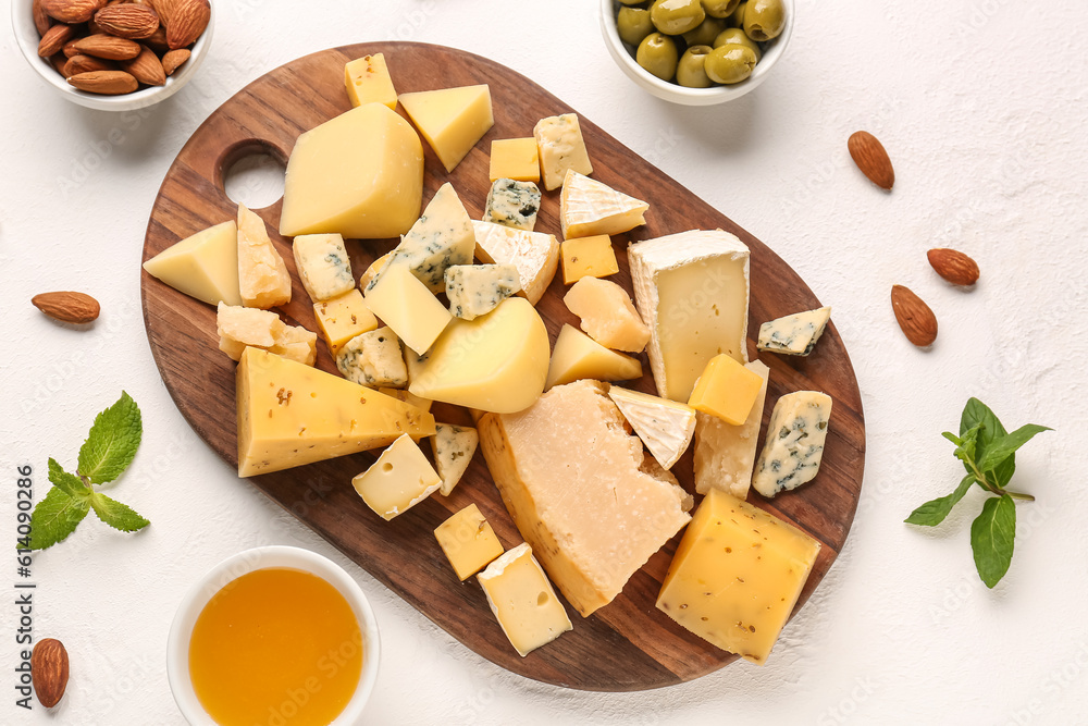 Wooden board with pieces of tasty cheese and honey on light background