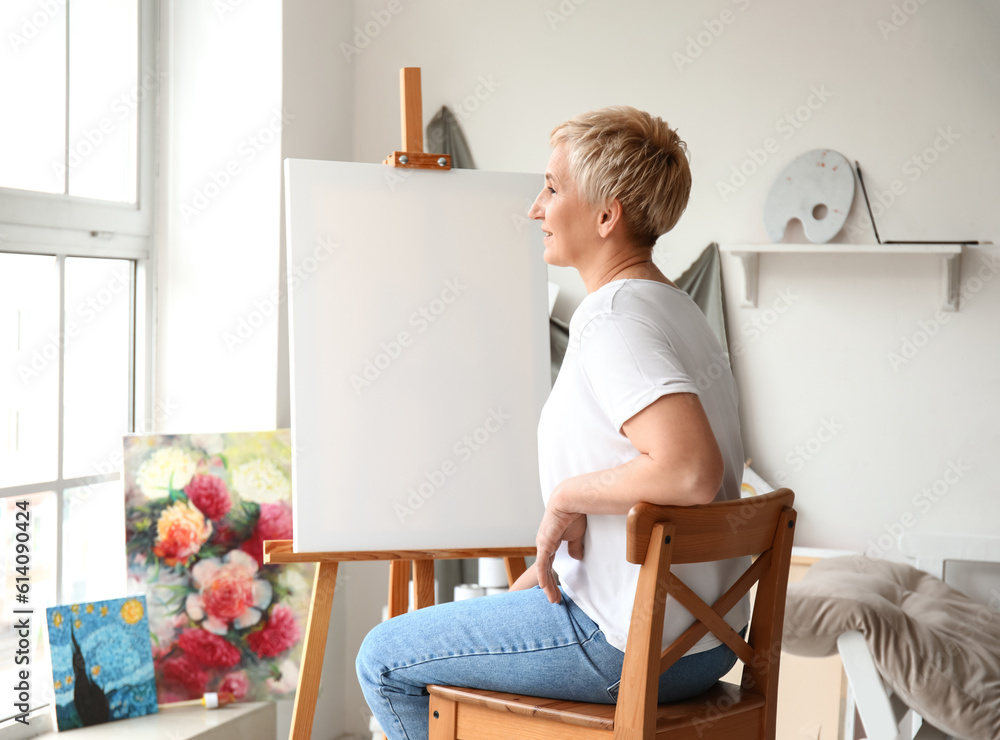 Mature female artist painting picture in  workshop