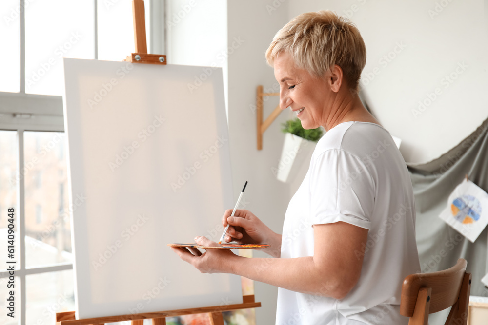 Mature female artist painting picture in  workshop