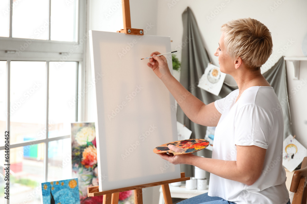 Mature female artist painting picture in  workshop