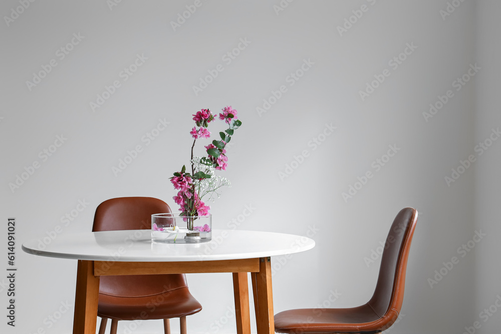 Beautiful ikebana on dining table in light room