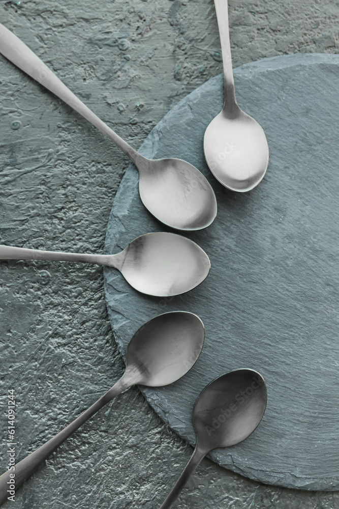 Board with stainless steel spoons on black background