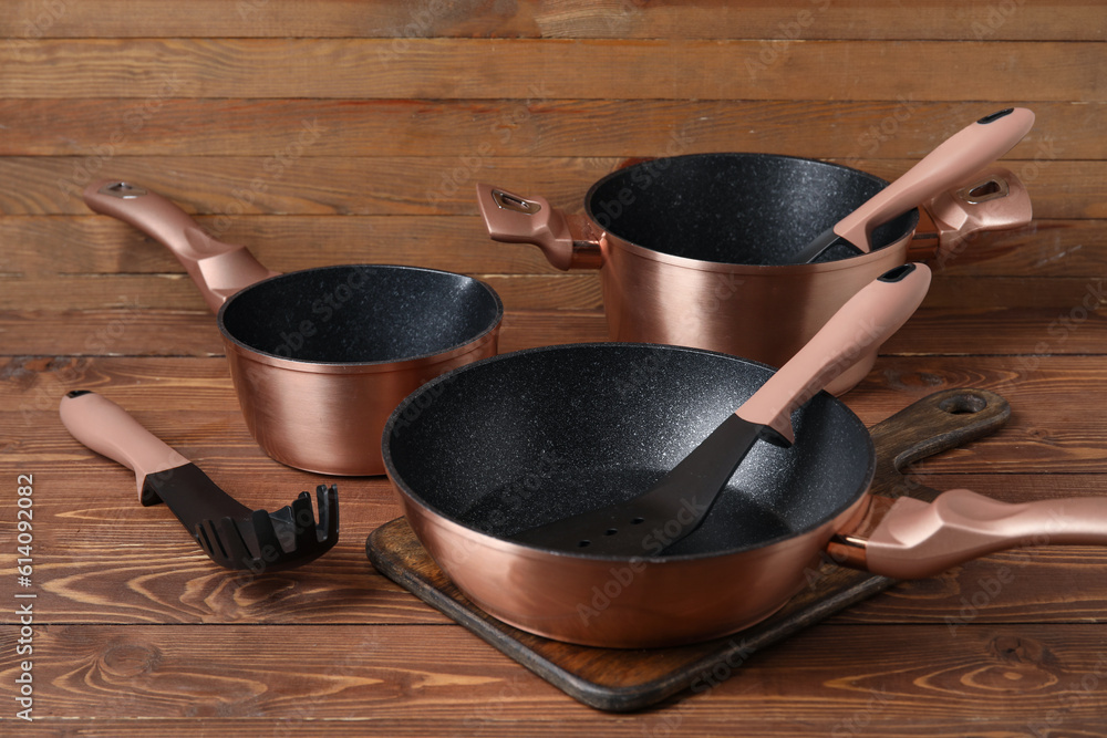 Set of copper cooking pots and kitchen utensils on wooden background