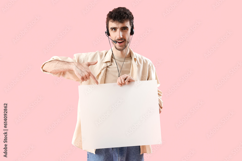 Male technical support agent with blank poster on pink background