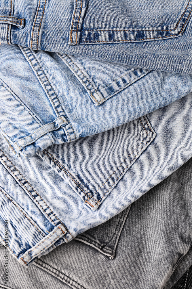 Different stylish folded jeans as background, closeup